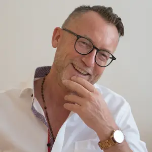 Therapiegespräch zwischen zwei Personen in einem modernen Raum, eine Person mit Klemmbrett hört aufmerksam zu.