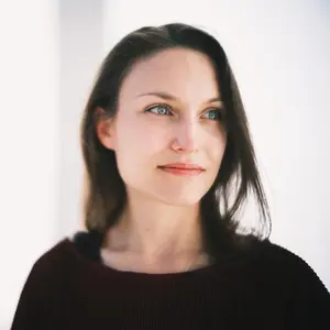 Therapiegespräch zwischen zwei Personen in einem modernen Raum, eine Person mit Klemmbrett hört aufmerksam zu.