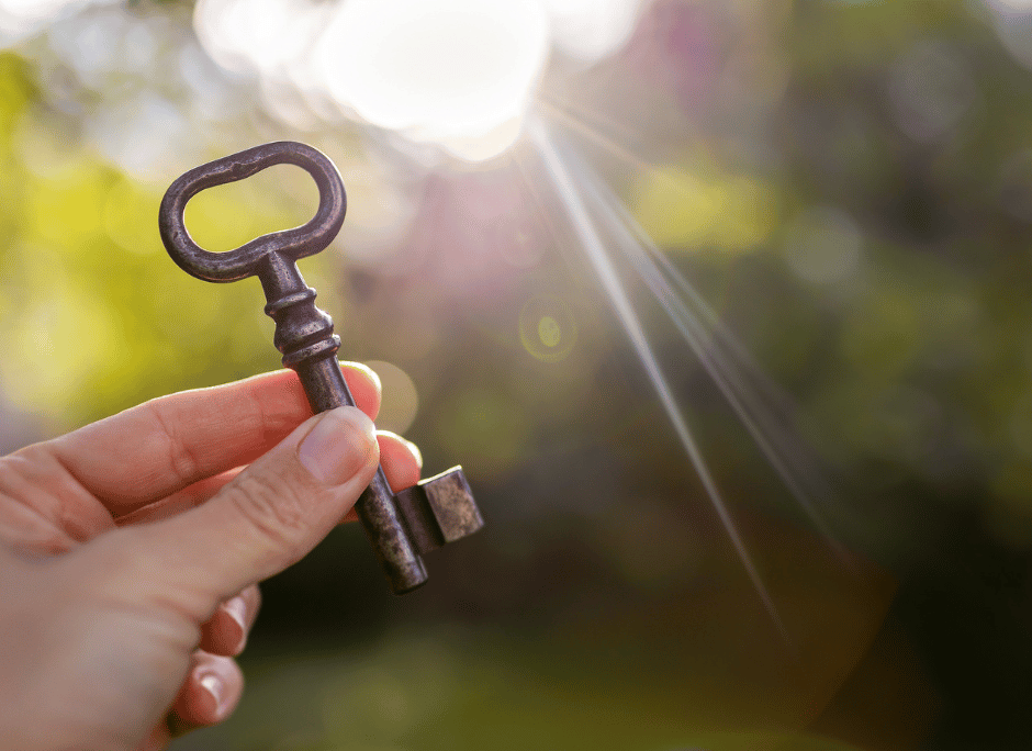 Einstiegsangebote Hand hält einen antiken Metallschlüssel vor unscharfem Hintergrund mit Sonnenlicht – Symbol für Zugang, Erkenntnis oder Potenzial.