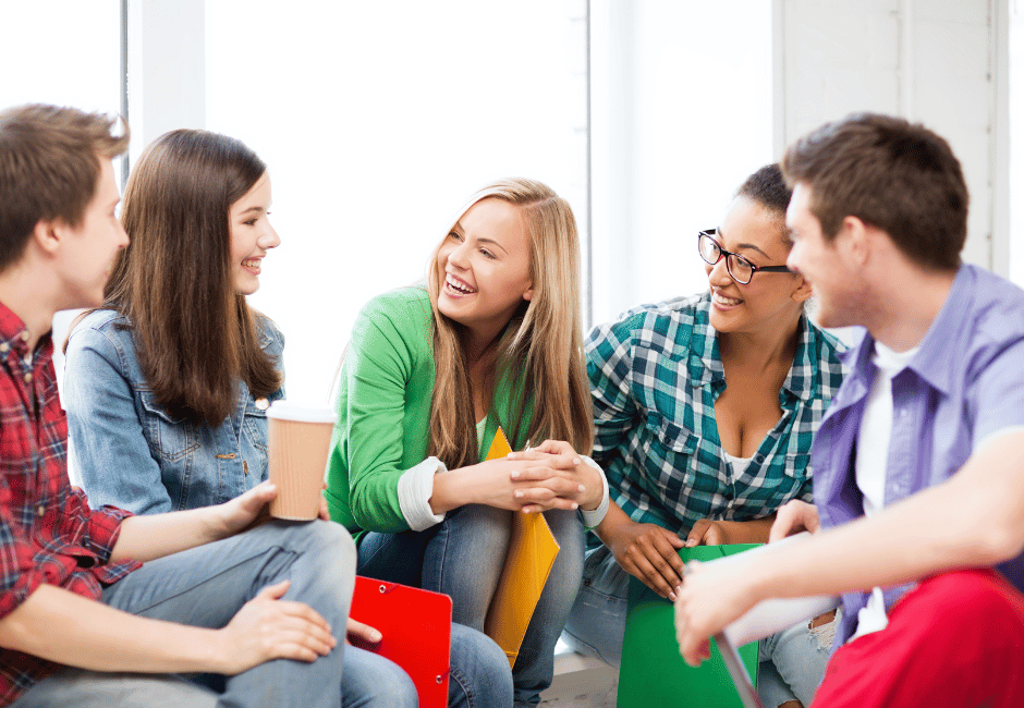 NLP-Basic Fünf junge Menschen sitzen in einem hellen Raum zusammen und unterhalten sich freundlich – Szene aus einem Lern- oder Austauschkontext.